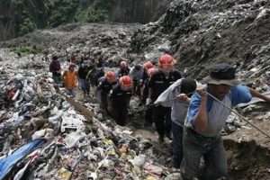 Rescue workers carry the body of a garbage scavenger who was killed in a mudslide caused by heavy rain in the city's main trash dump in Guatemala City, Friday, June 20, 2008. Six people rummaging through the trash died in the mudslide, according to authorities. (AP Photo/Moises Castillo)